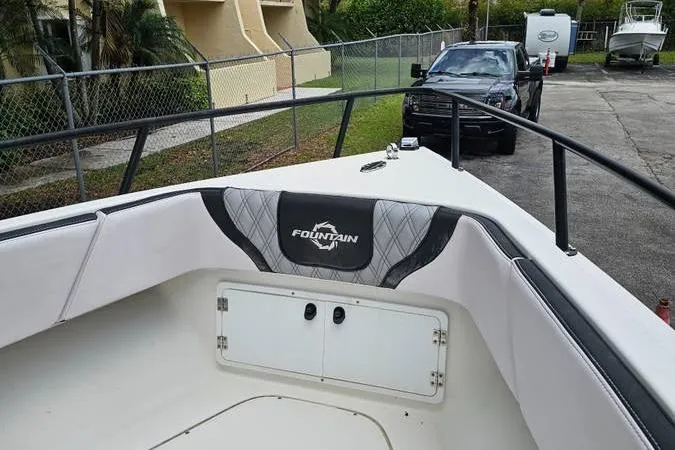 Slide: The Image of 1997 Fountain Sportfish 27 boat interior with logo, parked near a fence and vehicles. - 8