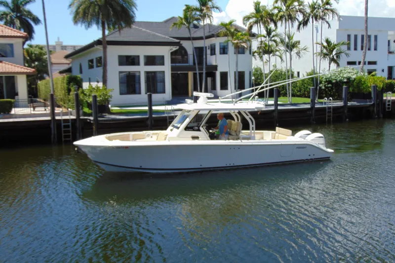 The Image of 2020 Pursuit S 328 Sport boat cruising near waterfront homes. - 0