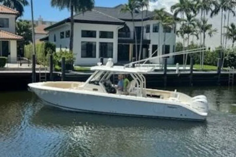 The Image of 2020 Pursuit S 328 Sport boat on a calm canal near luxury homes. - 1