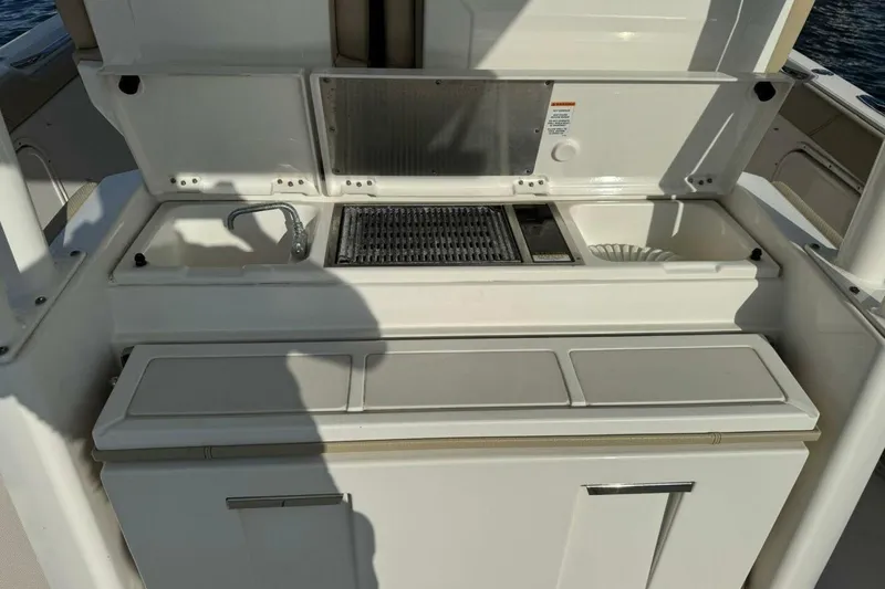 Slide: The Image of 2020 Pursuit S 328 Sport boat kitchen area with sink and grill. - 10
