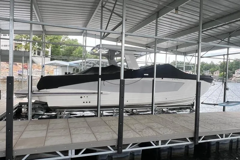 The Image of 2023 Aviara 36 boat docked under a covered marina, partially covered with a black tarp. - 1