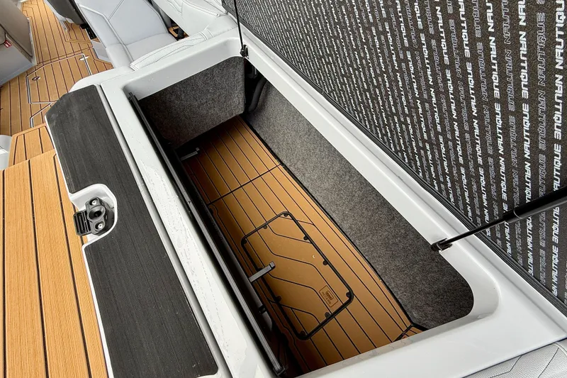 Slide: The Image of 2026 Nautique Super Air Nautique G23 storage compartment with teak flooring and branded interior. - 23