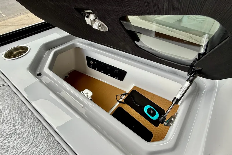 Slide: The Image of 2026 Nautique Super Air Nautique G23 storage compartment with cup holder and charging station. - 27
