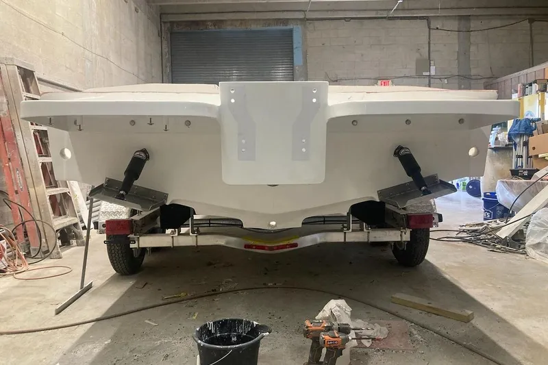 Slide: The Image of 2022 Paramount 21 boat in a workshop, rear view with trailer and tools. - 11