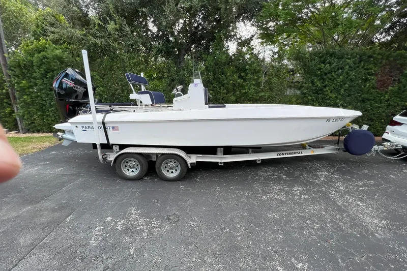 Slide: The Image of 2022 Paramount 21 boat on trailer, parked outdoors with lush greenery background. - 4