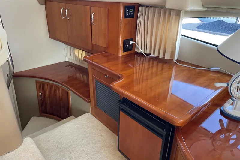 Slide: The Image of Interior of 2003 Carver 36 Sport Sedan with polished wood cabinetry and compact fridge. - 12