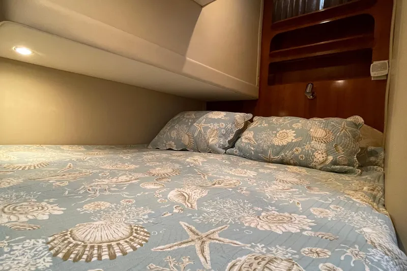 Slide: The Image of 2003 Carver 36 Sport Sedan cabin with seashell-themed bedding and cozy lighting. - 22