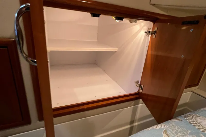 Slide: The Image of Open wooden cabinet inside 2003 Carver 36 Sport Sedan boat, showcasing interior storage space. - 24