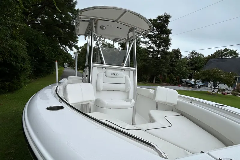 Slide: The Image of 2016 Sea Hunt Ultra 210 boat with white seating and T-top, parked on a grassy area. - 11