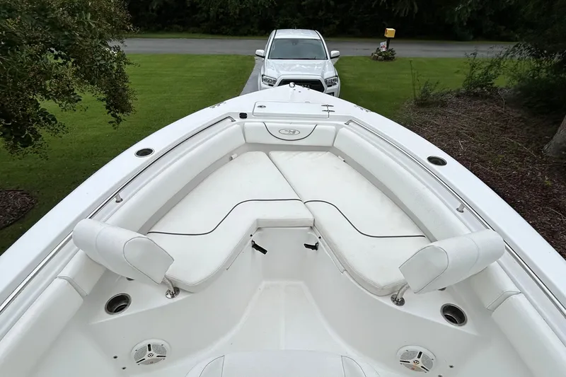Slide: The Image of 2016 Sea Hunt Ultra 210 boat interior with white seating, parked near a white vehicle. - 12