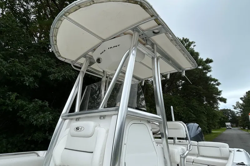 Slide: The Image of 2016 Sea Hunt Ultra 210 boat with T-top and seating, parked outdoors. - 13