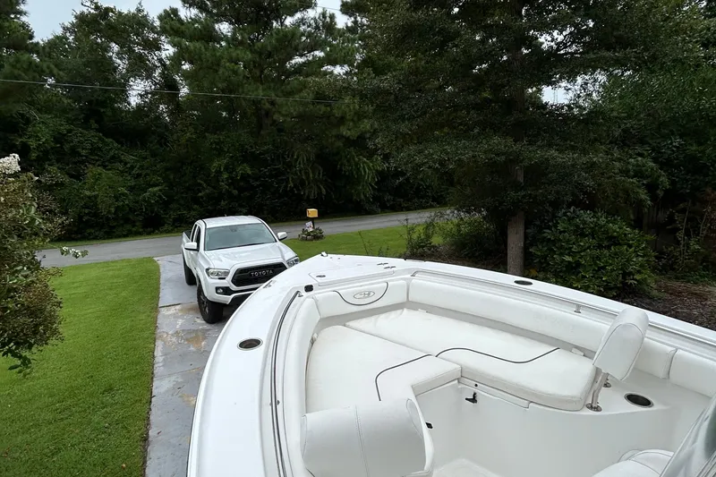 Slide: The Image of 2016 Sea Hunt Ultra 210 boat parked near a white truck in a driveway. - 16