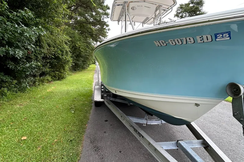 Slide: The Image of 2016 Sea Hunt Ultra 210 boat on trailer, parked beside lush greenery. - 18