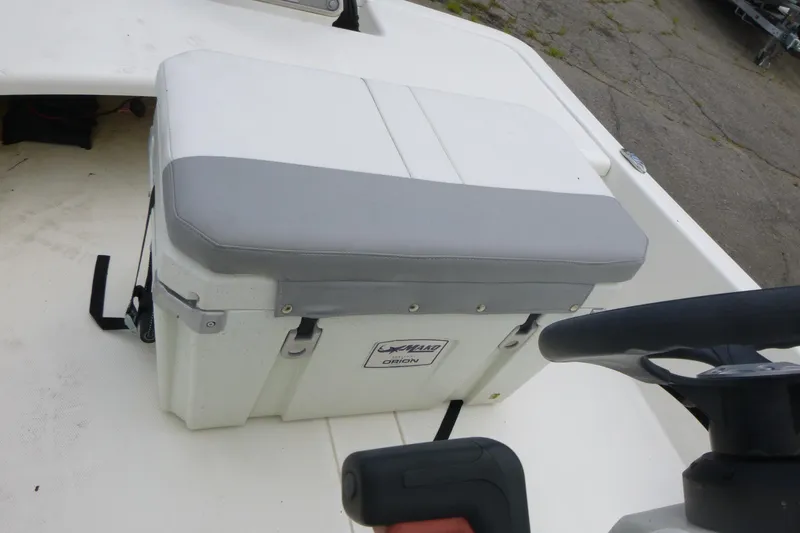 Slide: The Image of 2023 Mako Pro Skiff 15 CC boat interior with cushioned seat and steering wheel. - 10
