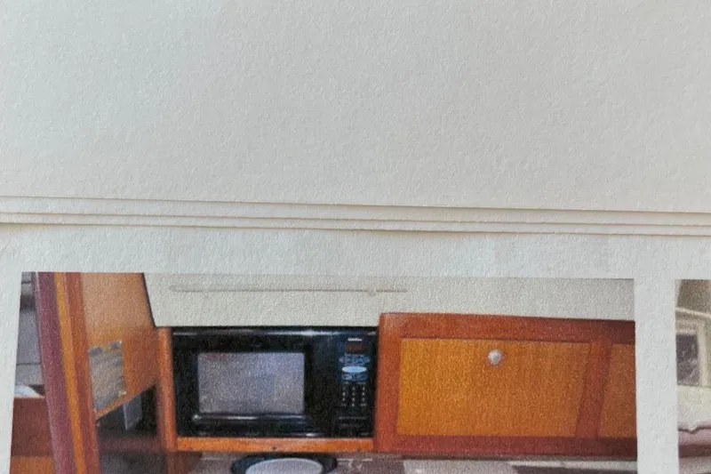 Slide: The Image of Interior of 1998 Hunter 340 sailboat kitchen with microwave and wooden cabinetry. - 14
