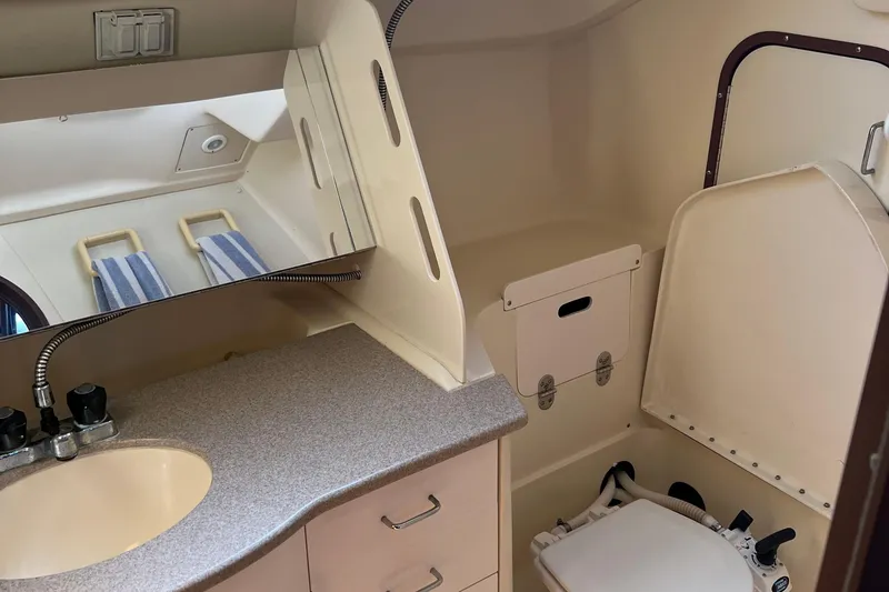 Slide: The Image of Bathroom interior of a 1998 Hunter 340 sailboat, featuring a sink, mirror, and marine toilet. - 19