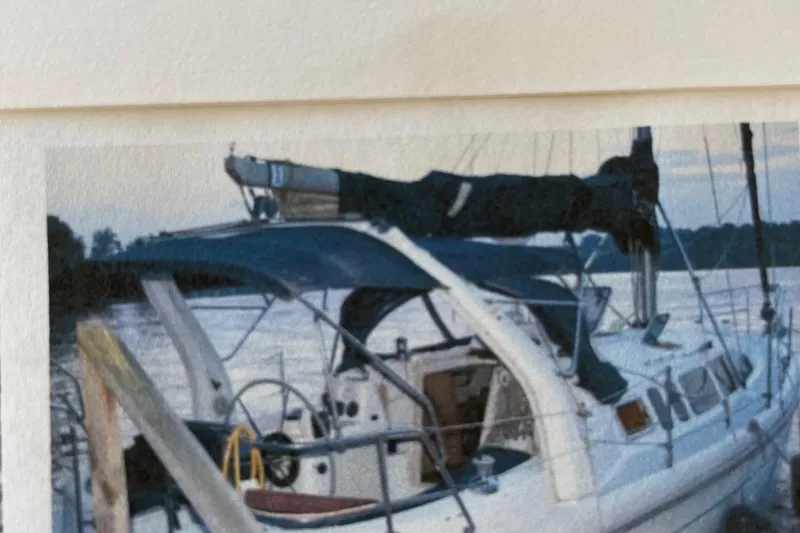 Slide: The Image of 1998 Hunter 340 sailboat docked by the water, featuring a blue canopy and steering wheel. - 5