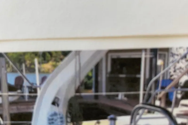 Slide: The Image of Blurred image of a 1998 Hunter 340 sailboat docked near a wooden pier. - 8
