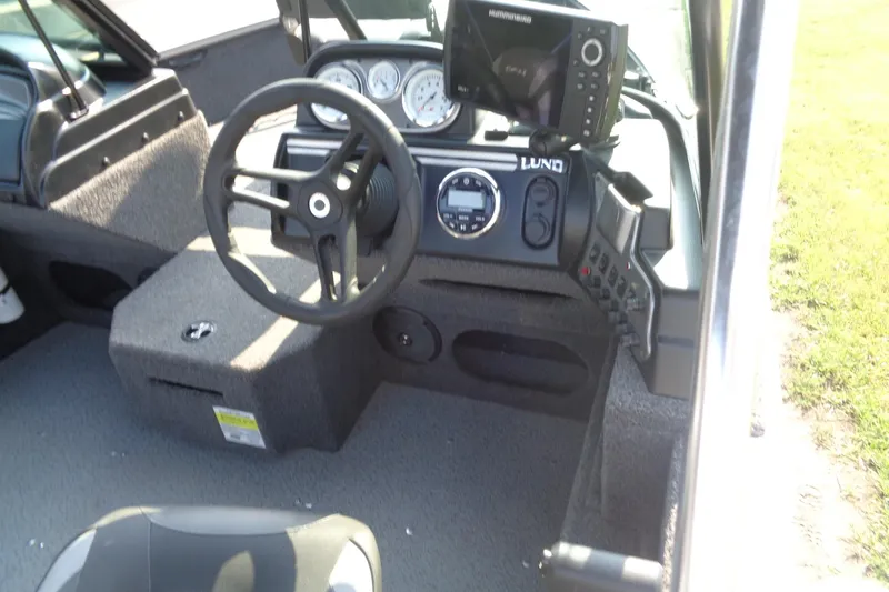 Slide: The Image of 2022 Lund 1675 Adventure Sport boat dashboard with steering wheel and navigation controls. - 13