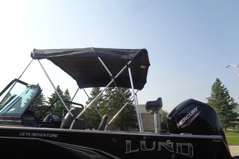 Slide: The Image of 2022 Lund 1675 Adventure Sport boat with canopy and Mercury engine, outdoors. - 15