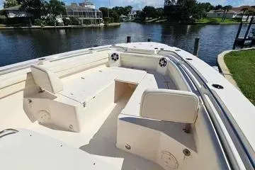 Slide: The Image of 2022 Grady-White Canyon 336 boat interior with seating, docked by a scenic waterfront. - 21