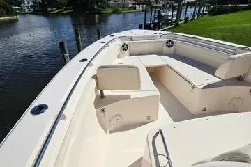 Slide: The Image of 2022 Grady-White Canyon 336 boat interior with seating, docked by a serene waterfront. - 22