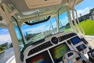 Slide: The Image of 2022 Grady-White Canyon 336 boat cockpit with advanced navigation systems and scenic waterway view. - 25