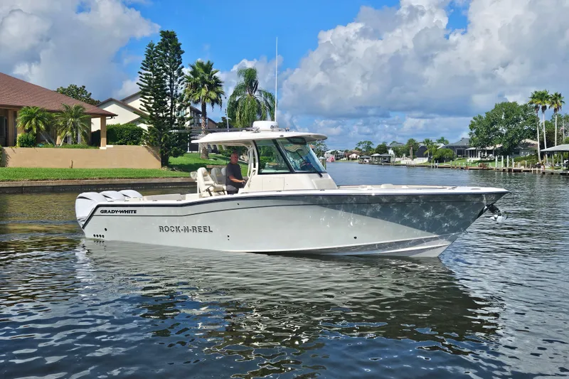 Slide: The Image of 2022 Grady-White Canyon 336 boat cruising on a scenic waterway under a blue sky. - 3