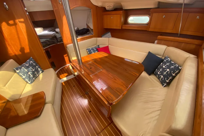 Slide: The Image of Interior of 2003 Hunter 386 sailboat with wooden table, beige seating, and nautical-themed cushions. - 10