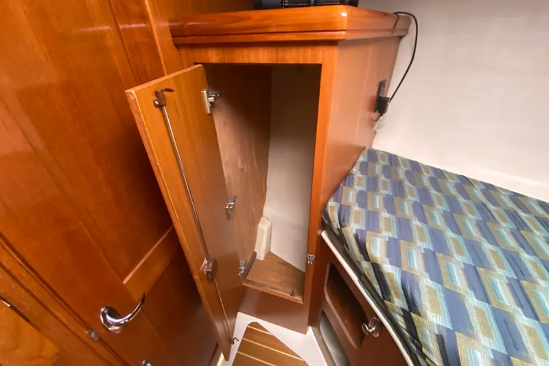 Slide: The Image of 2003 Hunter 386 yacht interior with open wooden cabinet and patterned bed. - 24