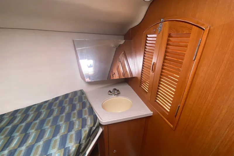 Slide: The Image of Interior of 2003 Hunter 386 sailboat with wooden cabinets and compact sink area. - 26