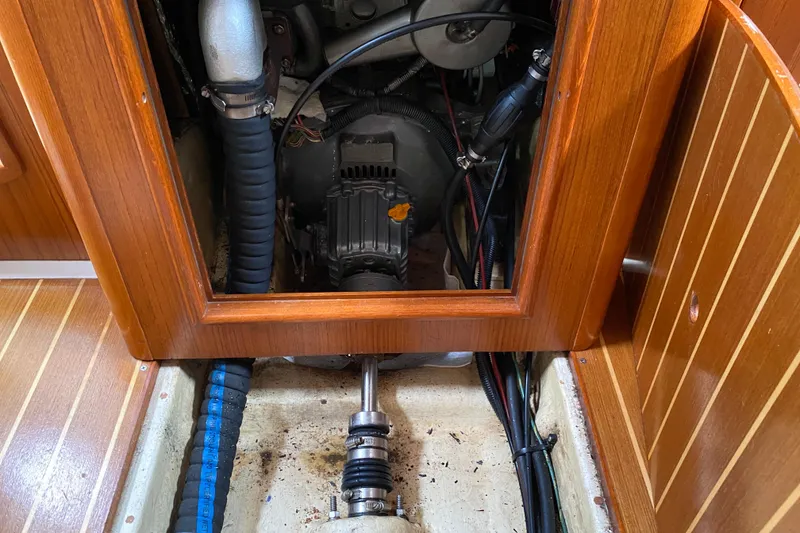 Slide: The Image of Engine compartment of a 2003 Hunter 386 sailboat, showcasing mechanical components and wooden paneling. - 54