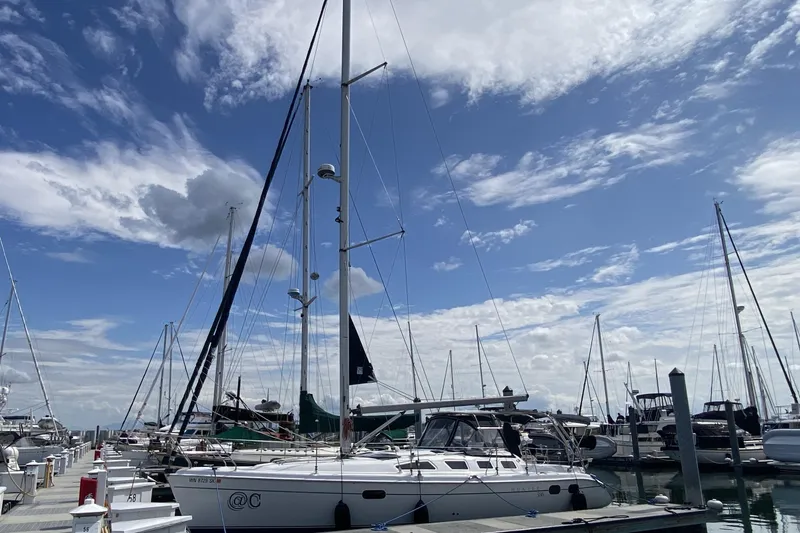 Slide: The Image of Sailboats docked at a marina under a partly cloudy sky, featuring a 2003 Hunter 386. - 87