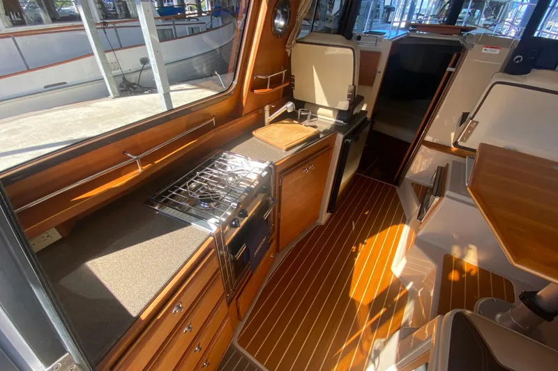 Slide: The Image of 2019 Ranger Tugs R-29 S interior with wood finish, compact kitchen, and seating area. - 39