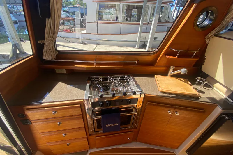 Slide: The Image of 2019 Ranger Tugs R-29 S interior kitchen with stove, sink, and wooden cabinetry. - 40
