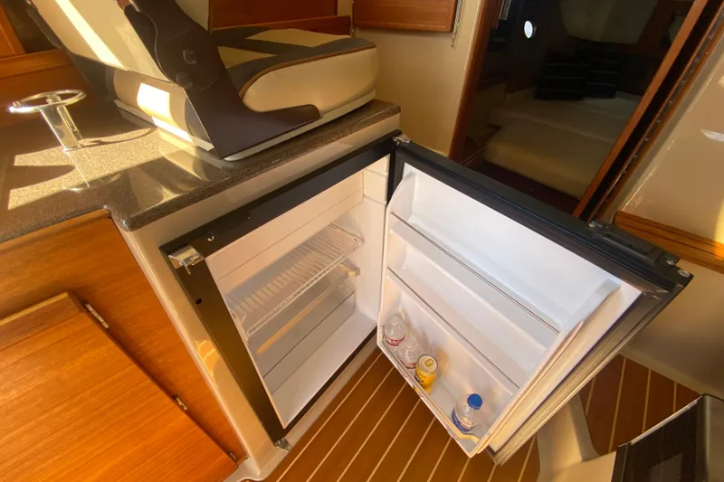 Slide: The Image of 2019 Ranger Tugs R-29 S interior with open mini fridge and seating. - 48