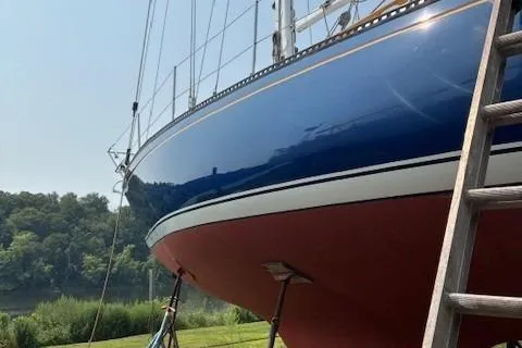 The Image of 1984 Catalina 38 sailboat on land, blue hull, red bottom, ladder nearby. - 0
