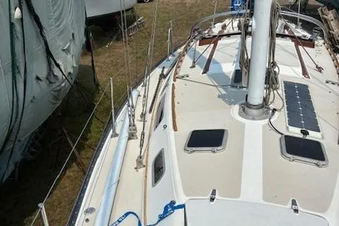 Slide: The Image of 1984 Catalina 38 sailboat deck with solar panel, docked on land. - 19