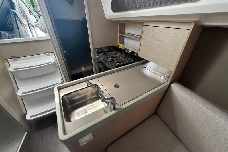 Slide: The Image of Compact kitchen area in a 2020 Beneteau Oceanis 30.1 sailboat, featuring a sink and stove. - 11