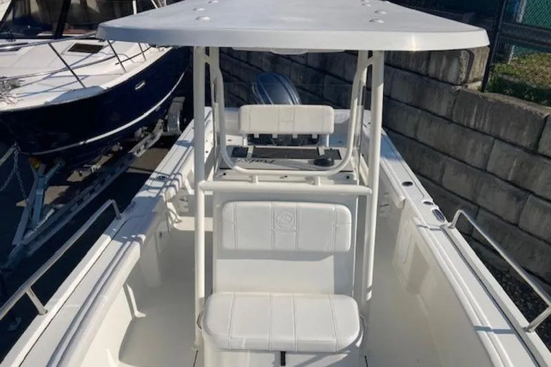 Slide: The Image of 2025 Parker 23 SE CC boat with center console and seating, docked beside another vessel. - 12