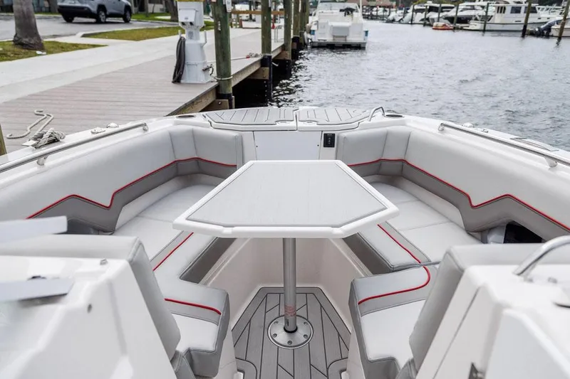 Slide: The Image of Manufacturer Provided Image: 2025 Solara S-250 DC boat interior with seating and table, docked by the waterfront. - 2