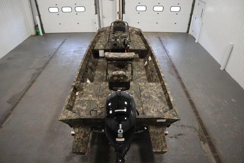 Slide: The Image of 2026 Lowe Roughneck RX2070 CC boat with camouflage design in a garage setting. - 40