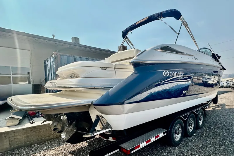 Slide: The Image of 2006 Cobalt 323 boat on trailer, blue and white, parked outdoors. - 15