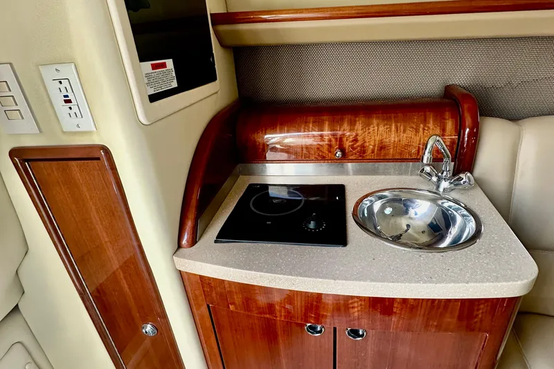 Slide: The Image of 2006 Cobalt 323 boat interior with wooden cabinetry, sink, and stovetop. - 2