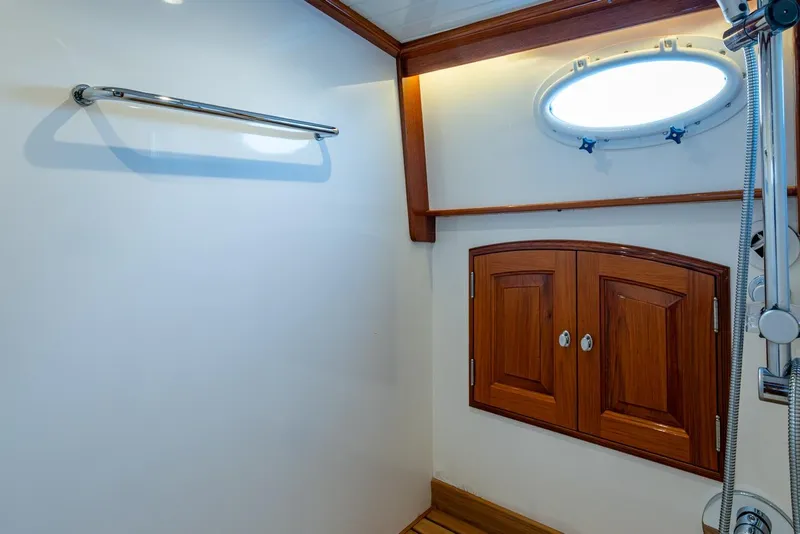 Slide: The Image of Interior of 2019 Hinckley T55 MKII Motor Yacht bathroom with wooden cabinets and porthole. - 34
