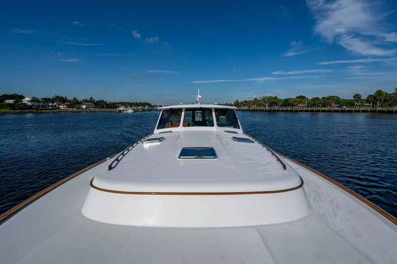 Slide: The Image of 2019 Hinckley T55 MKII Motor Yacht cruising on a serene waterway under a clear blue sky. - 48