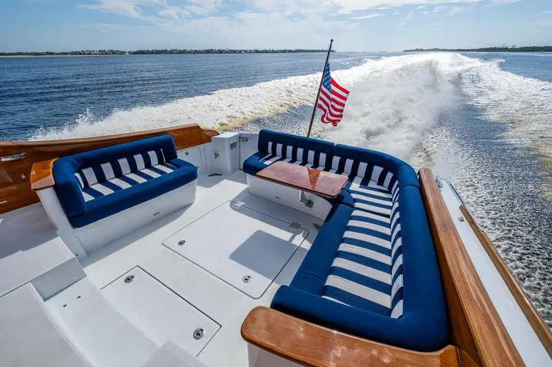 Slide: The Image of Hinckley T55 MKII Motor Yacht 2019, elegant deck with striped seating, American flag, ocean view. - 7