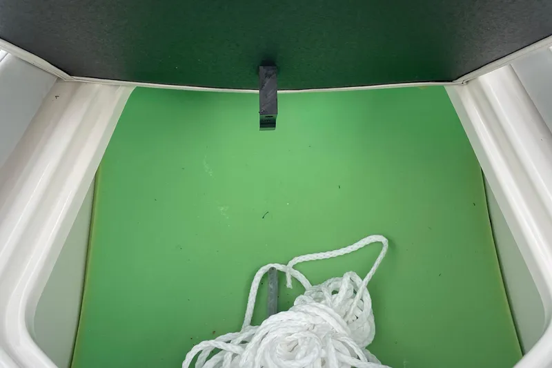 Slide: The Image of 2023 Bayliner VR5 boat storage compartment with green interior and white rope. - 12