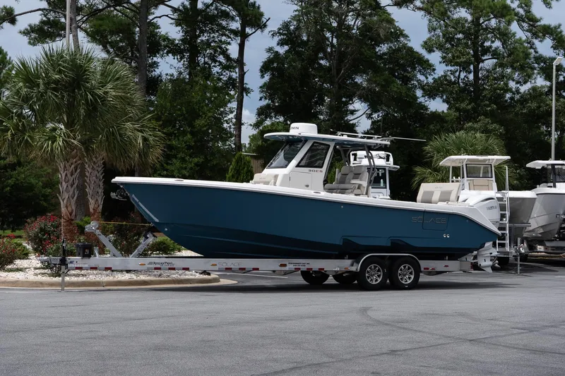 The Image of 2026 Solace 30 CS boat on trailer, surrounded by trees and parked outdoors. - 1