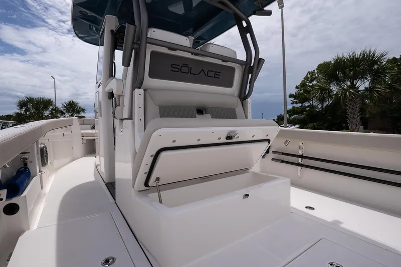 Slide: The Image of 2026 Solace 30 CS boat interior with open storage compartment, sleek design, and palm trees in background. - 12